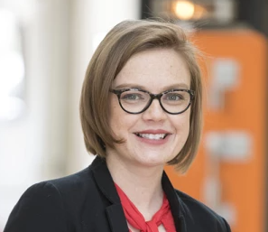 A close up to a smiling woman wearing glasses.